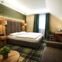 Deluxezimmer für zwei Personen mit Sofa, Schreibtisch und Vorhängen zum verdunkeln.